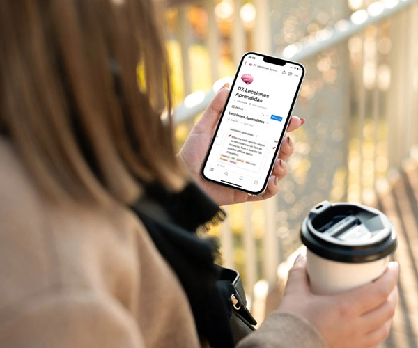 Mujer sosteniendo un café y un teléfono con una plantilla descargable